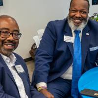 Two event guests sitting at table, smiling at camera